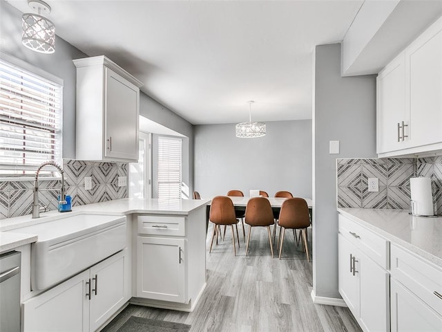 kitchen with backsplash, white cabinetry, and hanging light fixtures