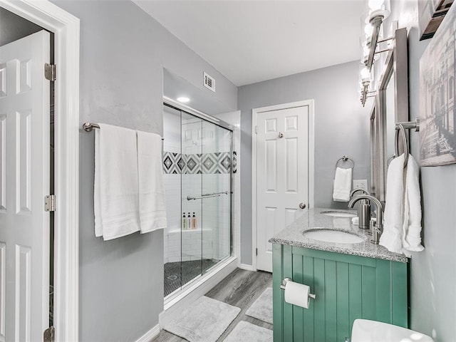 bathroom with wood-type flooring, a shower with door, and vanity