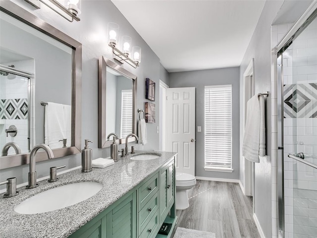 bathroom with hardwood / wood-style floors, toilet, a shower with shower door, and vanity