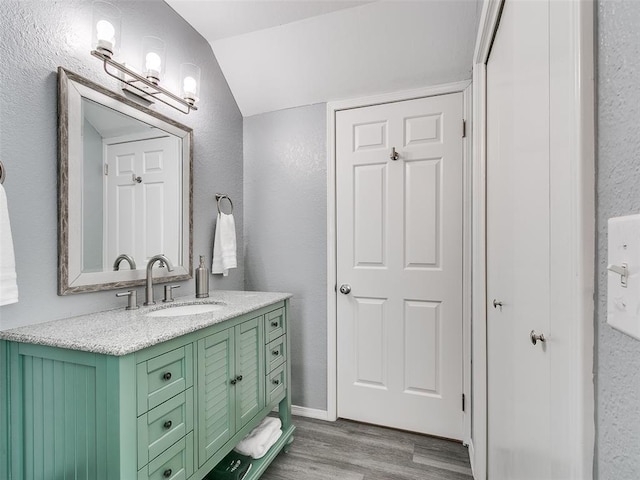 bathroom with vanity, vaulted ceiling, and wood-type flooring