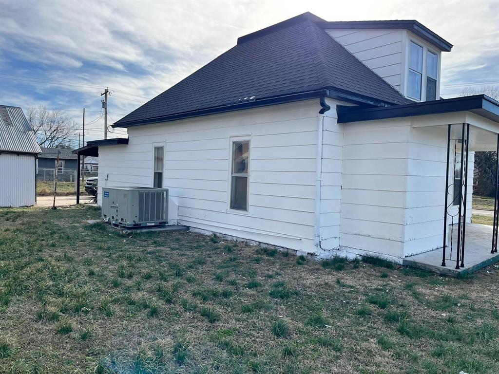 view of side of home featuring a yard and central AC