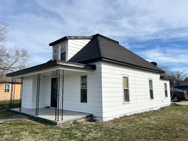 rear view of property featuring a yard, a patio, and covered porch