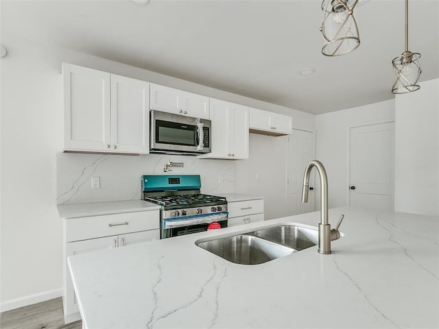 kitchen with light stone countertops, sink, decorative light fixtures, backsplash, and stainless steel appliances