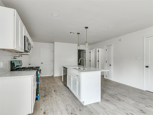 kitchen featuring sink, white cabinetry, stainless steel appliances, and an island with sink