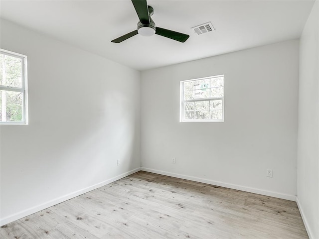 spare room with light wood-type flooring, ceiling fan, and a healthy amount of sunlight