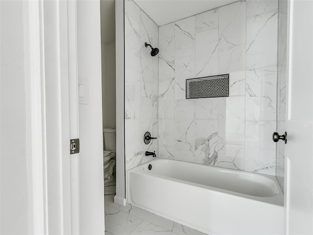 bathroom with toilet and tiled shower / bath