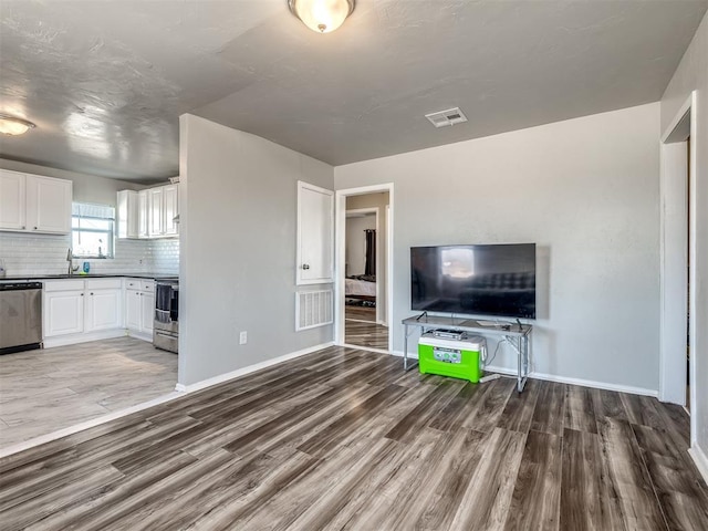 unfurnished living room featuring hardwood / wood-style flooring and sink