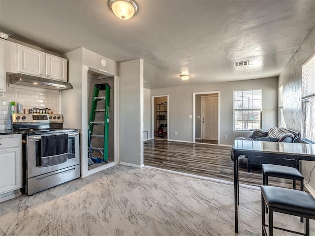 kitchen with backsplash, white cabinets, and stainless steel electric range