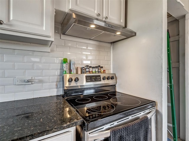 kitchen with stainless steel range with electric stovetop, dark stone counters, white cabinets, and tasteful backsplash