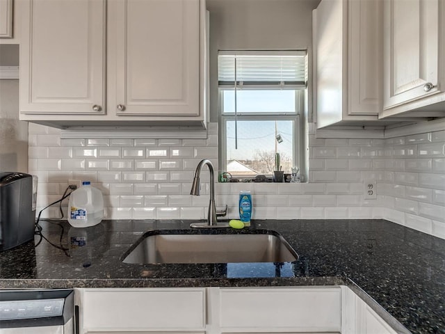 kitchen featuring dishwasher, sink, backsplash, white cabinetry, and dark stone countertops