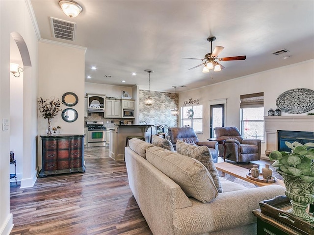 living room with ceiling fan, ornamental molding, and dark hardwood / wood-style floors