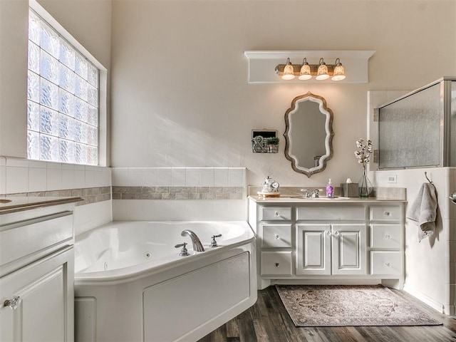 bathroom with hardwood / wood-style floors, a tub to relax in, and vanity