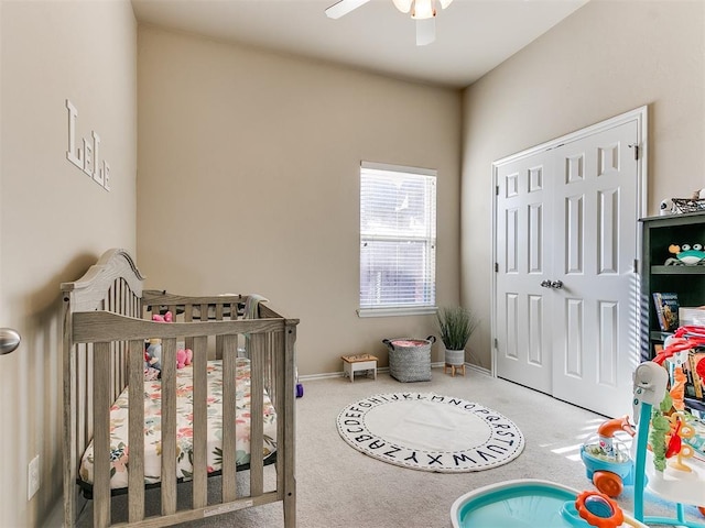 carpeted bedroom featuring a crib and ceiling fan