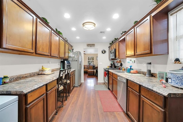 kitchen featuring appliances with stainless steel finishes, light stone countertops, and light hardwood / wood-style floors