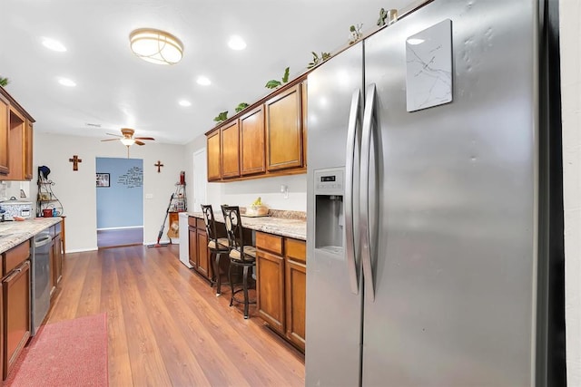 kitchen with stainless steel refrigerator with ice dispenser, ceiling fan, light stone counters, and light hardwood / wood-style floors