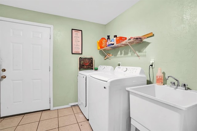 clothes washing area with washer and dryer, sink, and light tile patterned floors