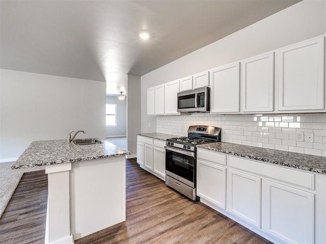 kitchen featuring white cabinetry, light stone countertops, an island with sink, and appliances with stainless steel finishes