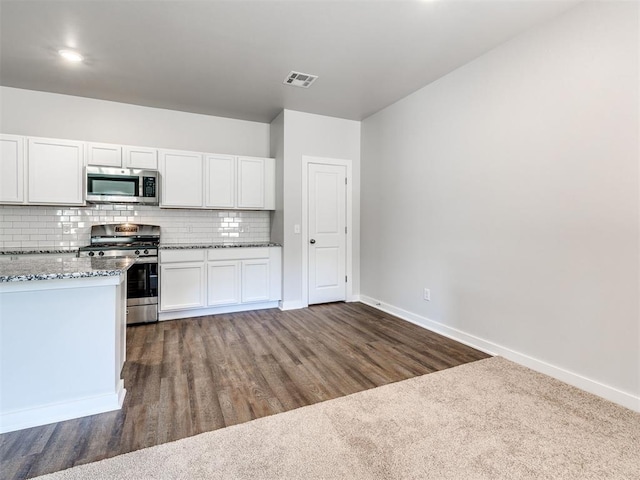 kitchen featuring appliances with stainless steel finishes, dark hardwood / wood-style floors, tasteful backsplash, light stone countertops, and white cabinets