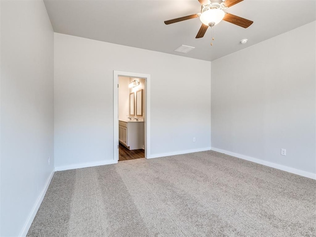 unfurnished bedroom with dark carpet, ceiling fan, and ensuite bathroom