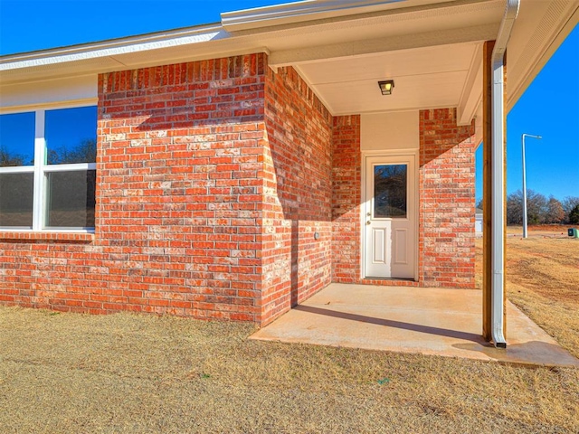 entrance to property with a lawn and a patio area