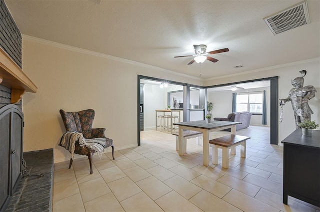 tiled dining room with ceiling fan, a fireplace, and crown molding