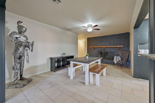 dining room with ceiling fan, light tile patterned floors, a brick fireplace, and ornamental molding