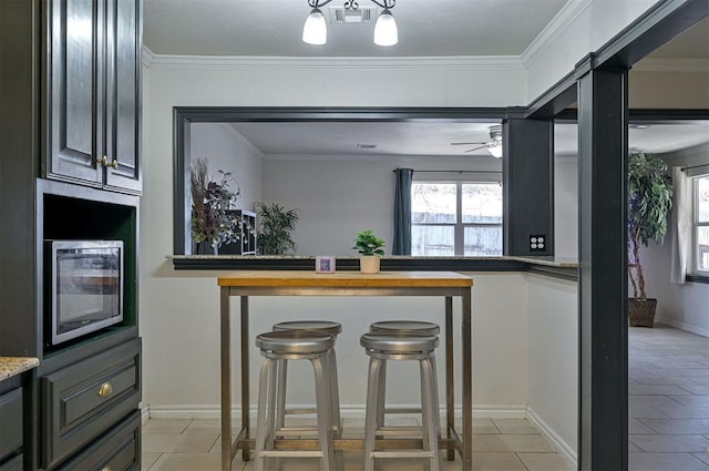 kitchen with ceiling fan, light tile patterned floors, and ornamental molding