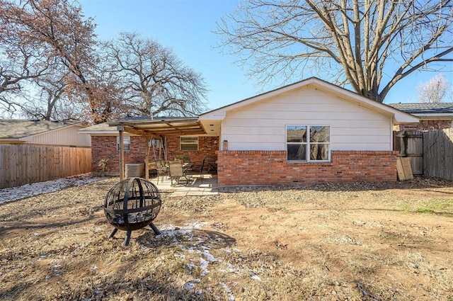 back of property with an outdoor fire pit, cooling unit, and a patio area