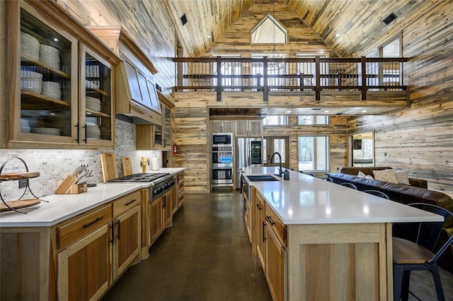 kitchen with a spacious island, sink, tasteful backsplash, appliances with stainless steel finishes, and wooden walls