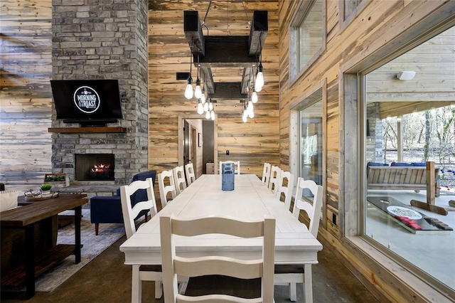 dining area with wood walls, a towering ceiling, and a fireplace