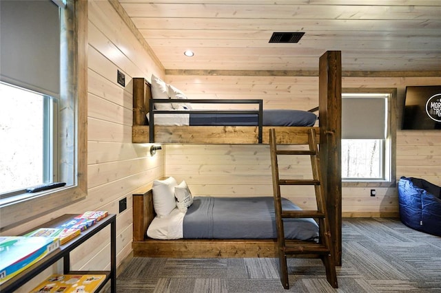 bedroom with wood ceiling, dark colored carpet, and wood walls