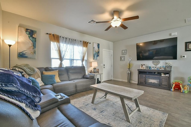 living room with ceiling fan, a fireplace, and wood-type flooring