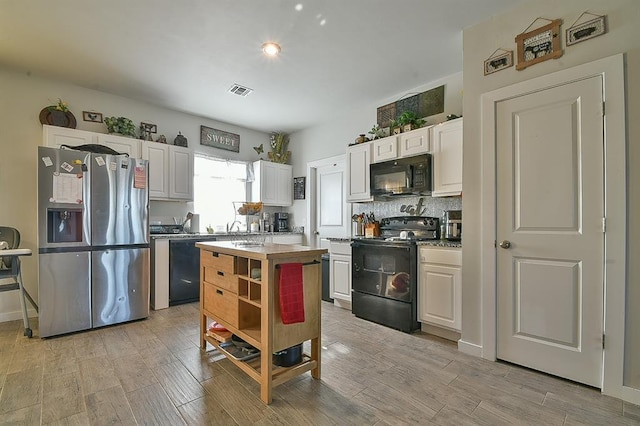 kitchen with sink, white cabinets, light hardwood / wood-style floors, black appliances, and decorative backsplash