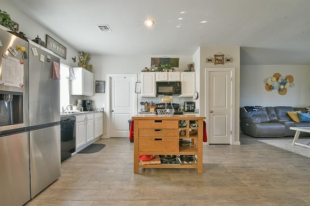 kitchen featuring black appliances, backsplash, white cabinets, and light hardwood / wood-style floors