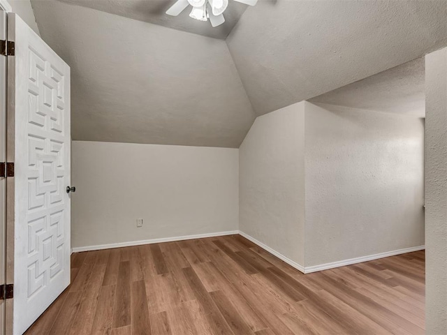 bonus room with a textured ceiling, vaulted ceiling, light hardwood / wood-style floors, and ceiling fan