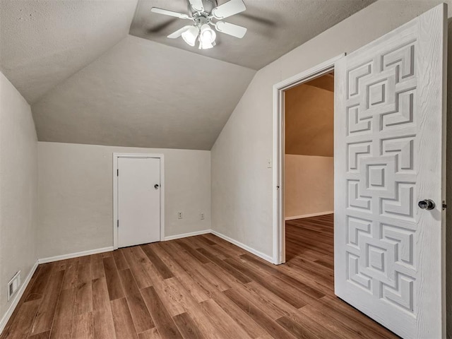 additional living space with ceiling fan, a textured ceiling, vaulted ceiling, and wood-type flooring