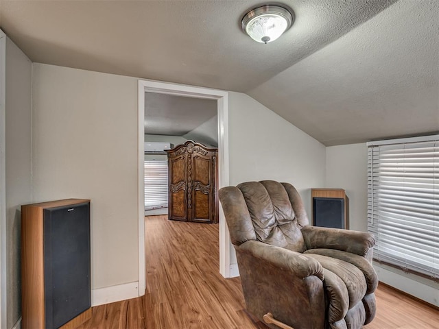 sitting room with lofted ceiling, a wealth of natural light, a textured ceiling, and light wood-type flooring