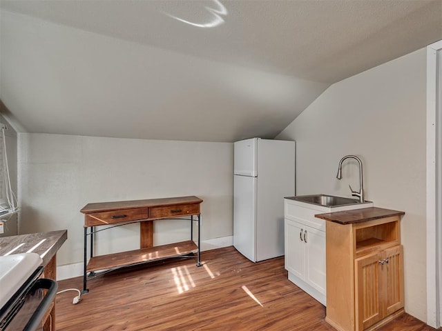 kitchen with hardwood / wood-style floors, lofted ceiling, sink, white refrigerator, and stove