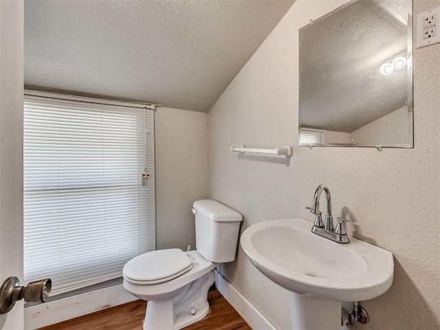 bathroom with lofted ceiling, toilet, sink, a textured ceiling, and hardwood / wood-style floors