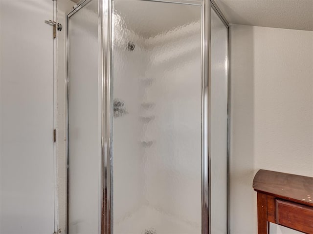 bathroom with a shower with door and a textured ceiling