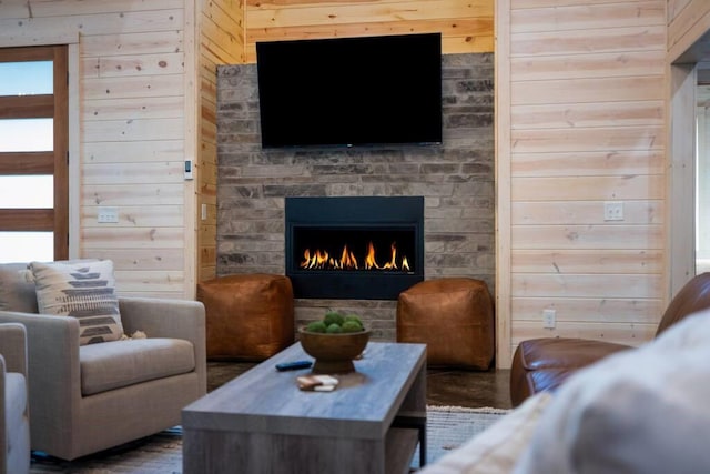 living room with wooden walls and a stone fireplace