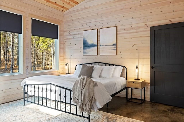 bedroom with concrete floors, wooden walls, and vaulted ceiling