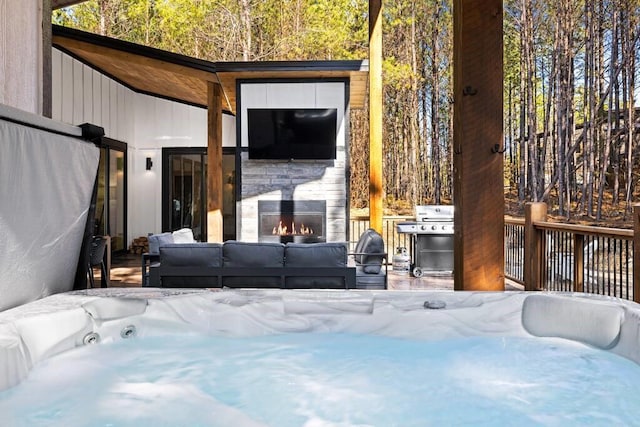 view of patio / terrace featuring an outdoor living space with a fireplace and a hot tub