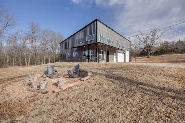 back of house with a garage, a yard, and a fire pit