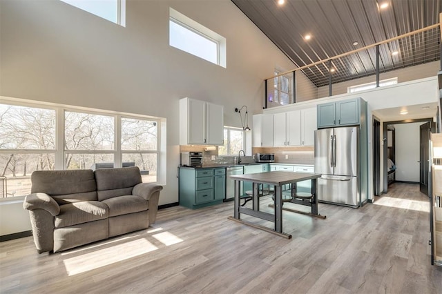 kitchen featuring light hardwood / wood-style floors, white cabinetry, appliances with stainless steel finishes, and a towering ceiling