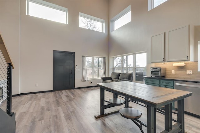 dining space featuring light hardwood / wood-style floors, a high ceiling, and plenty of natural light