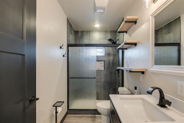 bathroom featuring hardwood / wood-style floors, toilet, a shower with door, and vanity