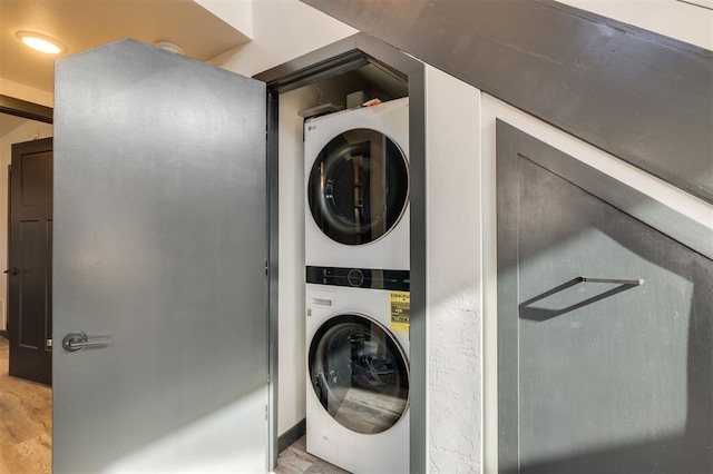 laundry room featuring stacked washer / drying machine and light hardwood / wood-style floors