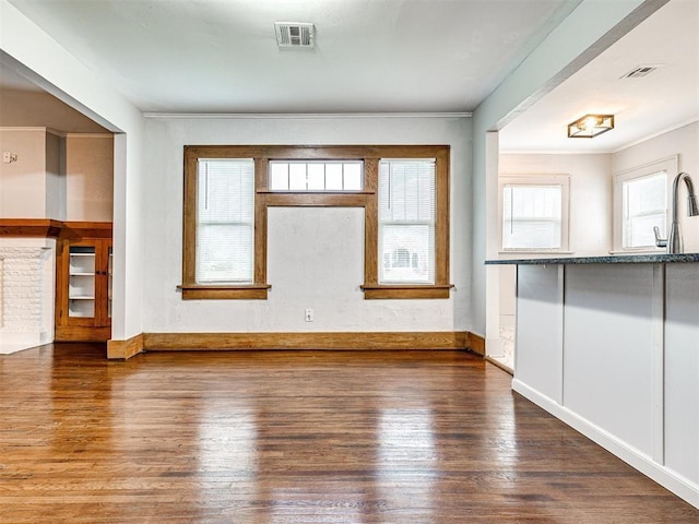 unfurnished living room with sink, hardwood / wood-style flooring, and ornamental molding