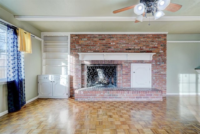 unfurnished living room with crown molding, ceiling fan, a fireplace, and light parquet floors